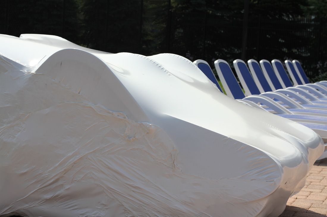 Outdoor lounge chairs protected by white shrink wrap